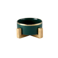Forest green gold-rimmed ceramic bowl on a wooden stand