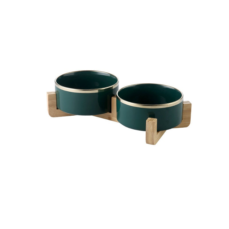 Pair of forest green gold-rimmed ceramic bowls on wooden stands
