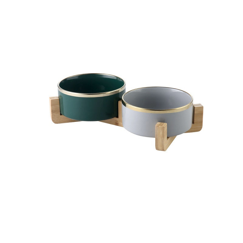 Pair of gold-rimmed ceramic bowls, one forest green and one dove grey, on wooden stands